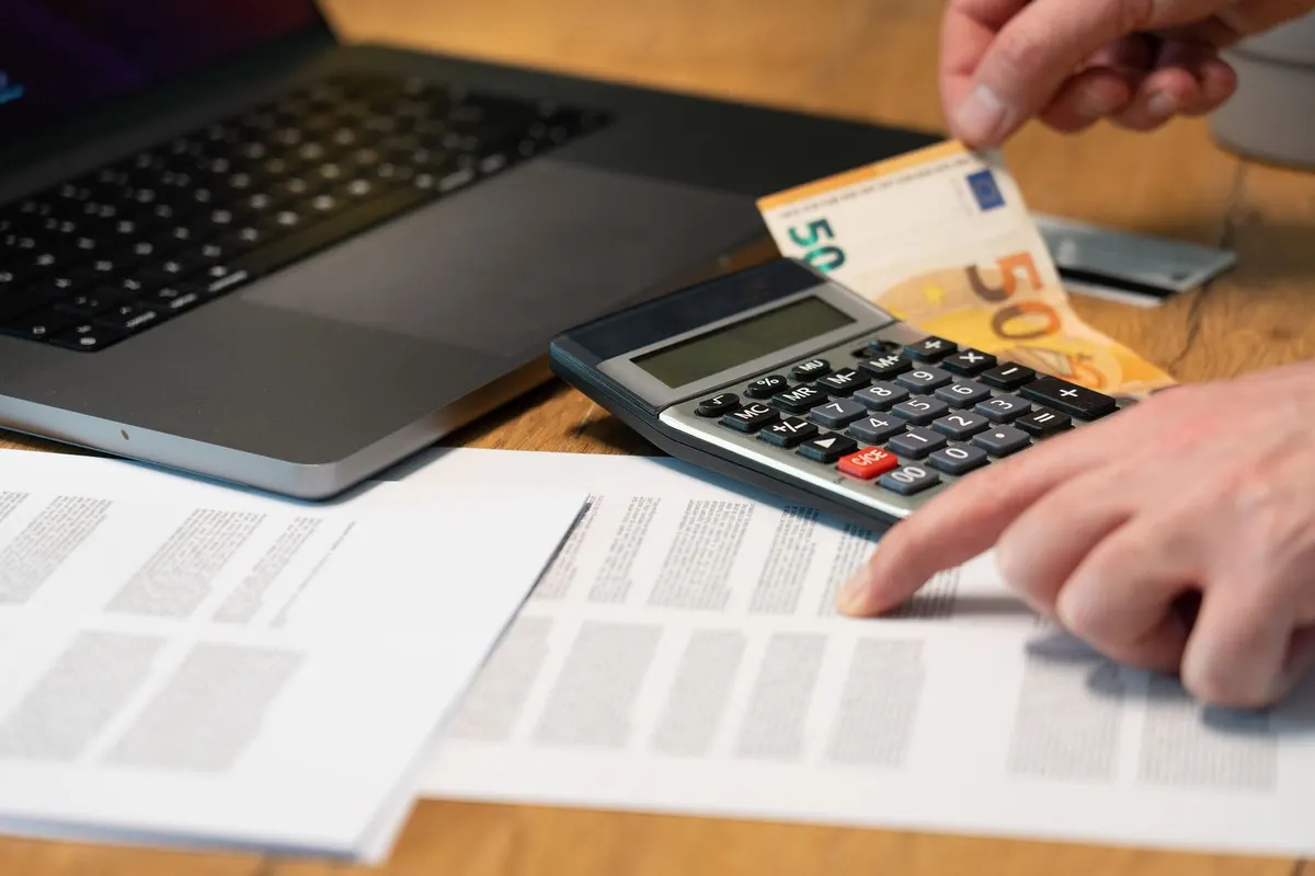 Papieren administratie met een rekenmachine en eurobiljetten op tafel