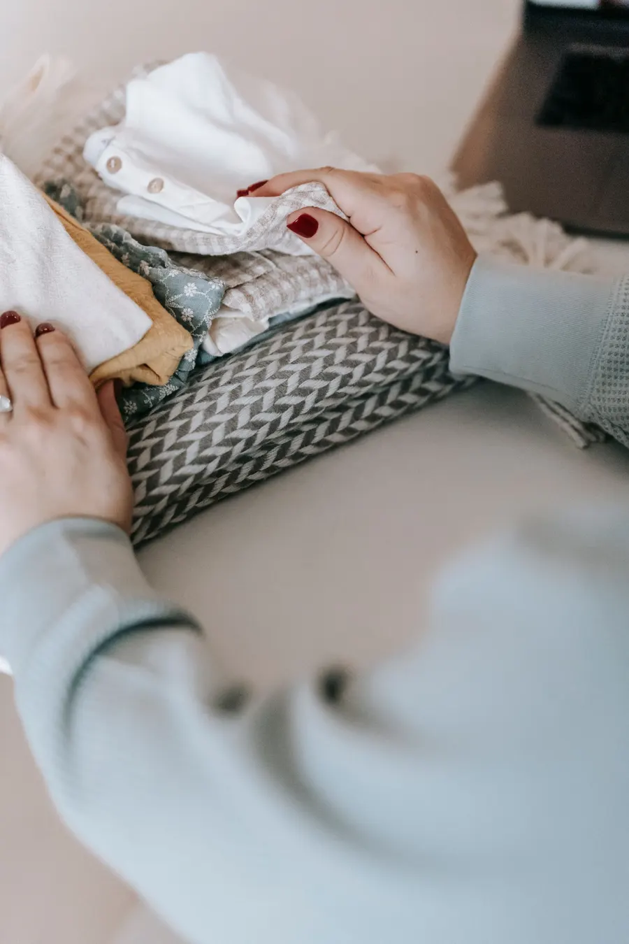 Handen vouwen kleding netjes op in een opgeruimde kast