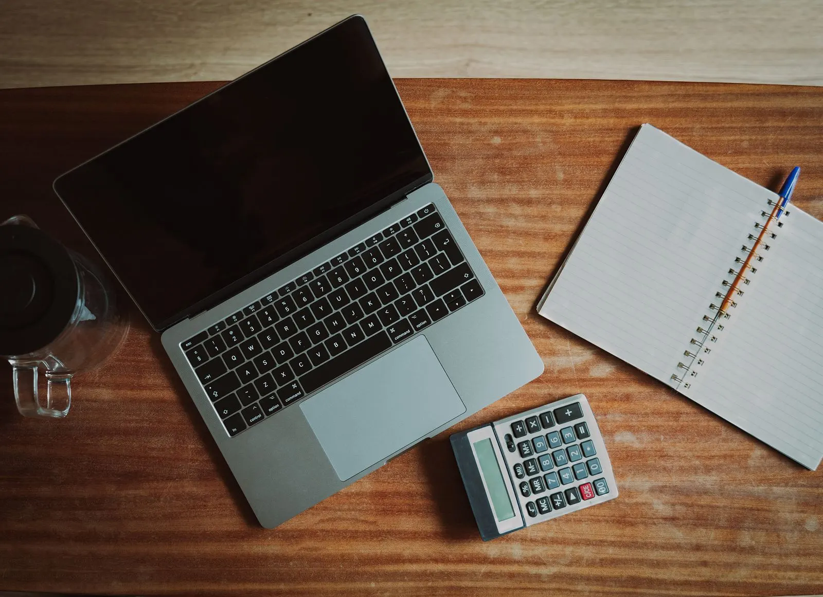Een opgeruimde werkplek met laptop, notitieboek en rekenmachine